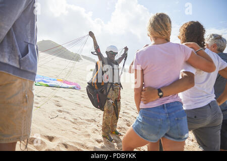 Gli studenti guardando maschio istruttore di parapendio con apparecchiature a sunny beach Foto Stock