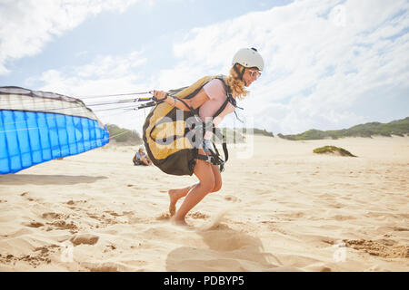 Femmina in esecuzione di parapendio con paracadute di sunny beach Foto Stock