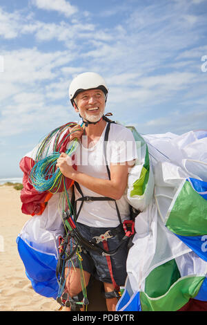 Sorridente maschio maturo di parapendio il trasporto di attrezzature e paracadute Foto Stock