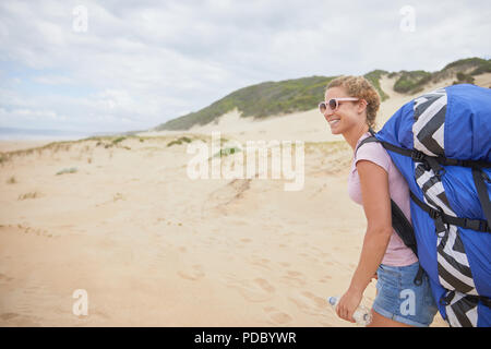 Donna sorridente parapendio con paracadute zaino sulla spiaggia Foto Stock