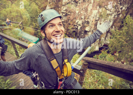 Ritratto sorridente e spensierato uomo preparando a zip line Foto Stock