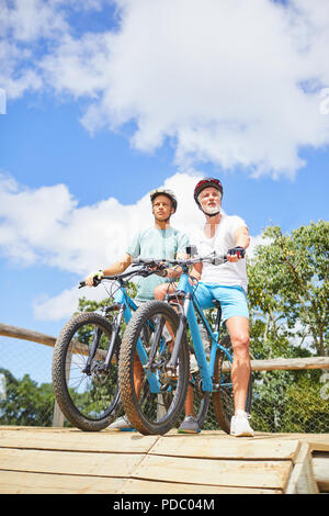 Padre e figlio in mountain bike alla corsa a ostacoli Foto Stock