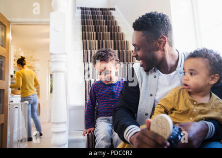 Padre mettendo le scarpe sul figlio bambino su scale Foto Stock