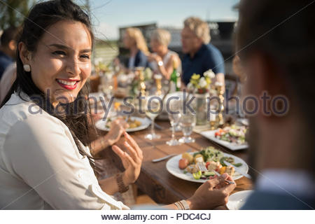 Donna sorridente, mangiare e parlare con un amico a sunny garden party pranzo