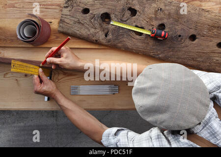 Carpenter lavorano il legno, misurando con setsquare e matita vecchio rustiche tavole in legno, vista dall'alto lo sfondo Foto Stock