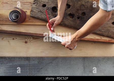 Carpenter lavorano il legno, misurando con metro e matita vecchio rustiche tavole in legno, vista dall'alto lo sfondo Foto Stock