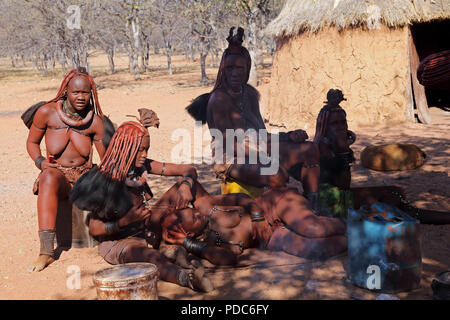 Le donne himba, Otjikandero village, Namibia settentrionale. Ocra rossa pasta è utilizzata per purificare la pelle e aiutare a proteggersi contro le punture di zanzara.. Foto Stock
