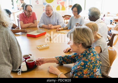 Senior amici giocare e bere il tè al tavolo nel centro della comunità Foto Stock