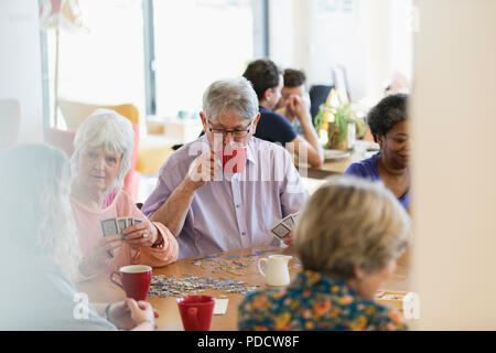 Senior amici giocare e bere il tè al tavolo nel centro della comunità Foto Stock