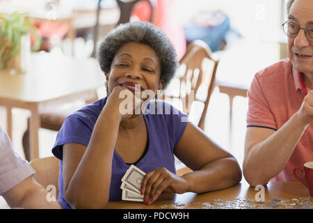 Fiducioso, felice donna senior giocando a carte con gli amici nel centro comunitario Foto Stock