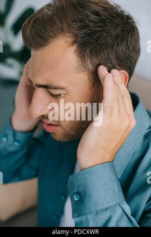 Vista ravvicinata del giovane uomo che soffre di mal di testa Foto Stock