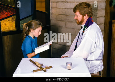 Ragazzo giovane leggendo la Bibbia al sacerdote durante la riconciliazione. © Myrleen Pearson ....Ferguson Cate Foto Stock