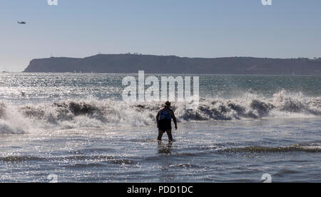 Una persona in piedi al mare come le onde si infrangono su Coronado Beach, San Diego. Foto Stock