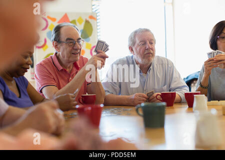 Senior amici a giocare a carte e bere il tè nel centro comunitario Foto Stock