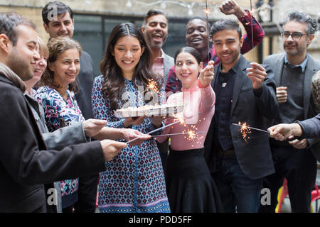 Amici con botti celebrando con donna holding torta di compleanno Foto Stock