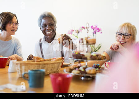 Felice senior amici gustando il tè del pomeriggio con i dessert in centro nella comunità Foto Stock