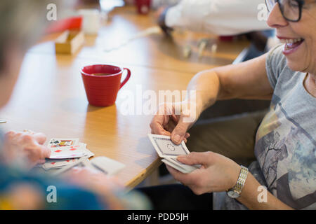 Senior donna giocando a carte con un amico in centro nella comunità Foto Stock