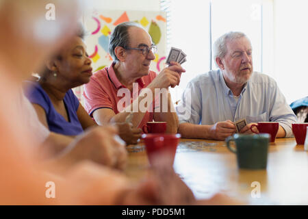 Senior amici giocando a carte in tavola nel centro comunitario Foto Stock