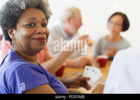 Ritratto fiducioso donna senior giocando a carte con gli amici nel centro comunitario Foto Stock