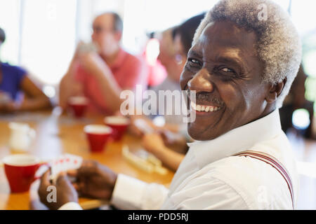 Ritratto felice uomo senior giocando a carte con gli amici nel centro comunitario Foto Stock