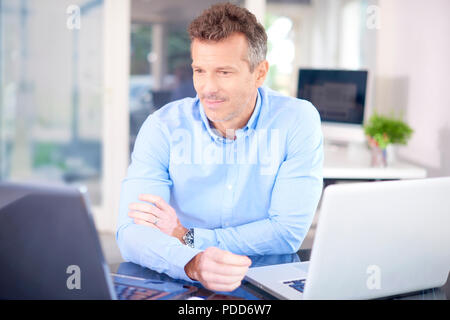 Colpo di imprenditore di pensiero seduti nella parte anteriore del computer portatile e guardando attentamente mentre si lavora sul nuovo progetto. Foto Stock