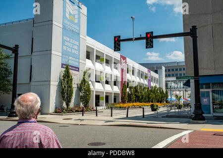 L'uomo attraversando la strada per andare al patio all'aperto presso il centro mercantile in Worcester, MA Foto Stock