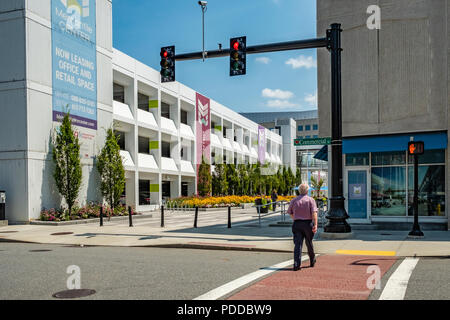 L'uomo attraversando la strada per andare al patio all'aperto presso il centro mercantile in Worcester, MA Foto Stock