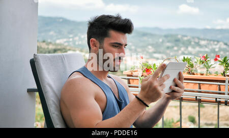 Uomo che lavora al computer Tablet sul balcone Foto Stock