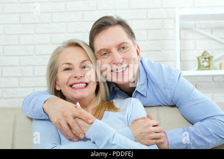 Primo piano della allegro eccitato felice felicemente felice con toothy sorriso splendente bionda attraente donna e uomo, egli abbraccia il suo da dietro e baci Foto Stock