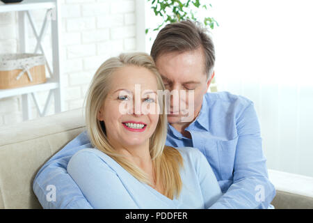 Primo piano della allegro eccitato felice felicemente felice con toothy sorriso splendente bionda attraente donna e uomo, egli abbraccia il suo da dietro e baci Foto Stock