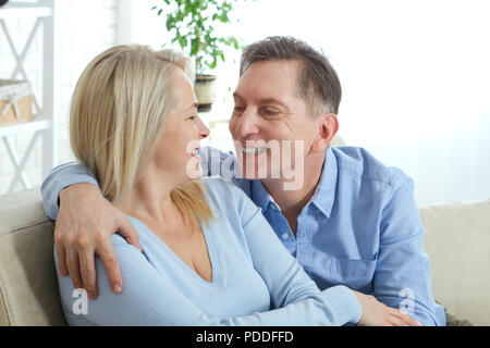 Giovane a casa sul divano a parlare e sorridente. Primo piano Foto Stock