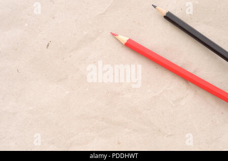 Si torna a scuola, sfondo minima, una matita rossa e una matita nera su carta marrone, ad alto angolo di visione, grande spazio di copia Foto Stock