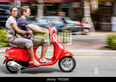 Miami Beach Florida,Washington Avenue,uomo uomini maschio,donna donna donne,rosso,scooter a motore,trasporto alternativo,senza casco,non sicuro,coppia,due 2 Foto Stock