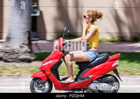 Miami Beach Florida,Fifth 5th Street,adult adults donna donna donna donna donna donna donna donna donna, rosso, scooter moto, giro, ciclomotore, moto alternativa tra Foto Stock