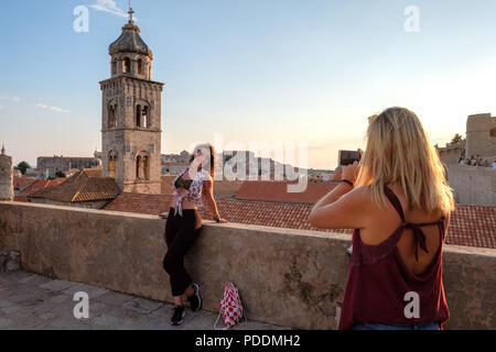 I turisti a scattare foto di un amico nella vecchia città di Dubrovnik con il suo smartphone Foto Stock