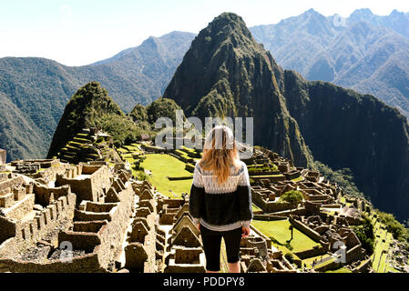 La donna da dietro e si affaccia il complesso archeologico di Machu Picchu. Più popolari mete di viaggio, wanderlust. Regione di Cuzco, Perù. Lug 2018 Foto Stock