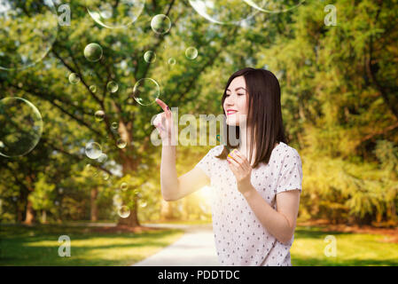 Carino donna le catture bolla di sapone in estate park Foto Stock