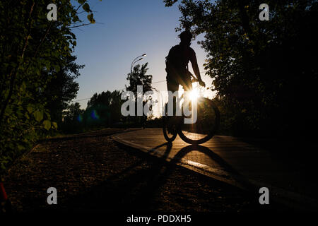 Immagine del ciclista che indossa il casco equitazione intorno città in serata Foto Stock