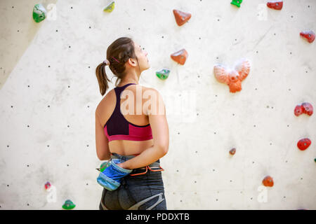 Foto dal retro della donna atleta con la sacca di talco sullo sfondo della parete per arrampicata su roccia Foto Stock