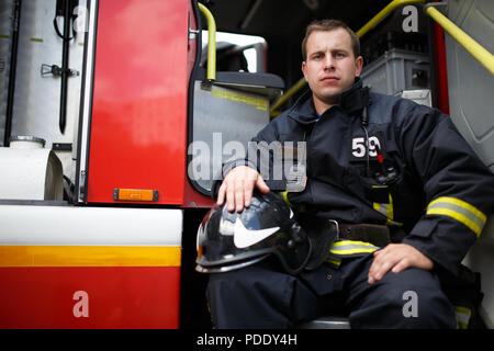 Foto di giovani fireman guardando la fotocamera in camion dei pompieri Foto Stock