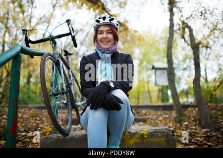 Immagine della ragazza seduta sulle scale accanto alla bicicletta Foto Stock