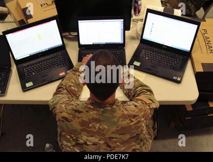 Army Sgt. Kyle Plumley, un analista di Intel per forza comune sede fuori di Columbus, Ohio, opere tre computer portatili possono 16 come parte di Cyber scudo 2018 a Camp Atterbury, ind. Cyber Shield offre una formazione collettiva evento che in parte si prepara ai soldati di monitorare attivamente per la rete interna di minacce. Foto Stock