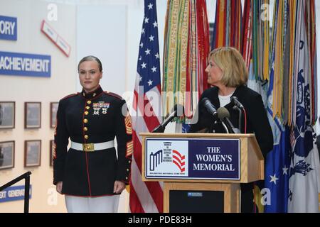 Master Sgt. Meghann Viggiani sorge all attenzione mentre sost. Claudia Tenney, New York congressista, fornisce osservazioni durante le donne nei militari ghirlanda di cerimonia di posa, sponsorizzato dal Congressional Caucus per le questioni femminili, Arlington, Virginia, 17 maggio 2018. Viggiani, riconosciuto per il suo coraggio e risultati professionali, è il capo di logistica a caserma marini Washington, e fu il Marine Corps' eccezionale femmina senior noncommissioned officer presso l'evento. La cerimonia annuale che si è tenuto presso le donne in servizio militare per l'America Memorial, onora le donne attraverso tutte le filiali Foto Stock