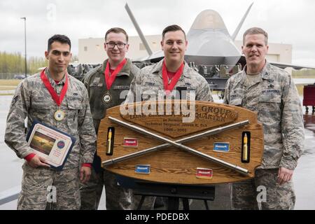 Stati Uniti Air Force Col. Mathew Powell, comandante del terzo gruppo di manutenzione, presenta un trofeo al personale Sgt. Randall Stoiner, Airman 1. Classe Giuseppe pagina e Senior Airman Justin Rios come stanno di fronte a un F Raptor dopo l'ala trimestrale carico di armi Crew concorrenza Maggio 18, 2018 a base comune Elmendorf-Richardson, Alaska. Powell è stata congratulandosi con il carico di armi equipaggio dal novantesimo Manutenzione aeromobili Unità sezione armi per vincere la concorrenza. Foto Stock