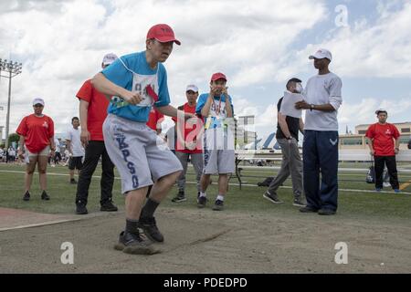 Un atleta terre nella sabbia durante la standing salto in lungo la concorrenza della pianura di Kanto Special Olympics a Yokota Air Base, Giappone, 19 maggio 2018. Per questo anno di giochi, oltre 300 atleti di tutte le età da 10 diverse scuole locali hanno gareggiato per l'oro. Foto Stock