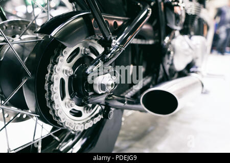 Dettaglio di un motociclo catena posteriore con tubi di scarico. Vista posteriore di un motociclo con il focus sulla catena. Foto Stock