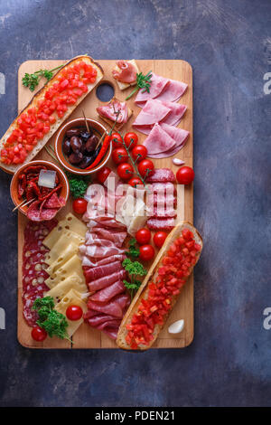 Salame, prosciutto, salsicce, prosciutto, formaggio, pomodoro. Carne Antipasto scheda sul tavolo di pietra. Vista da sopra con copia spazio. Foto Stock