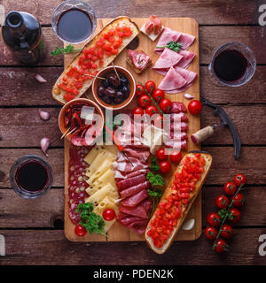 Vino rosso con salumi assortimento on dark tavolo rustico, laici piatta Foto Stock