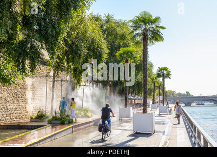 Persone che passeggiano e percorsi in bicicletta lungo la Senna a Parigi, Francia, durante Paris-Plage evento estivo mentre altri cool stesse verso il basso sotto l'acqua sigg. Foto Stock