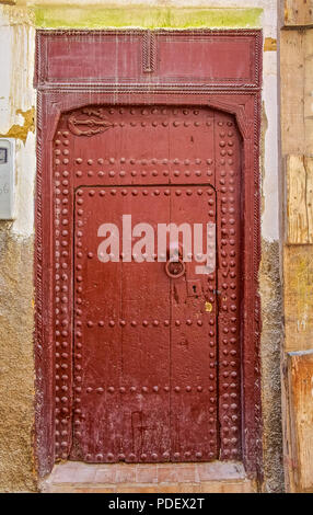 Vecchio di Legno complessamente intarsiato, studded porta e porta-cornice,di un Marocchino tradizionale casa di Fez, Marocco Foto Stock